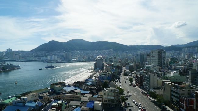 도로와 자동차, 건물 너머로 바다와 산을 내려다 보며 찍은 사진