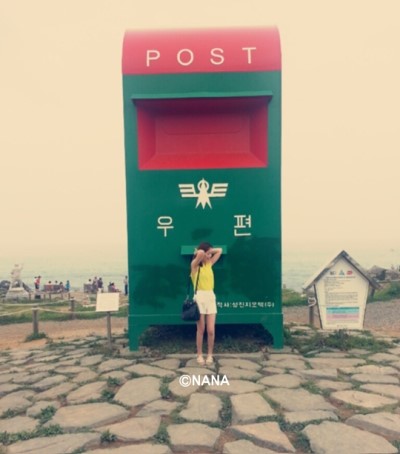 울산 간절곶의 커다란 우체통 앞에 한 여자가 서 있다.